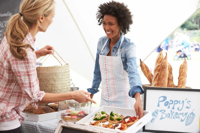 A woman sells baked goods at a farmers market. self-employed professionals can harness the benefits of mileage reimbursement to enhance their financial well-being and drive success in their entrepreneurial endeavors.