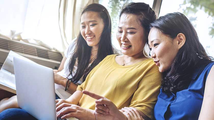 mother-daughters-look-at-laptop-smiling