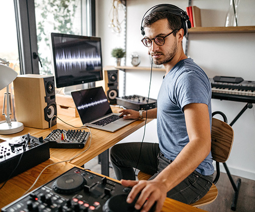 Man with glasses using a DJ setup to make music.