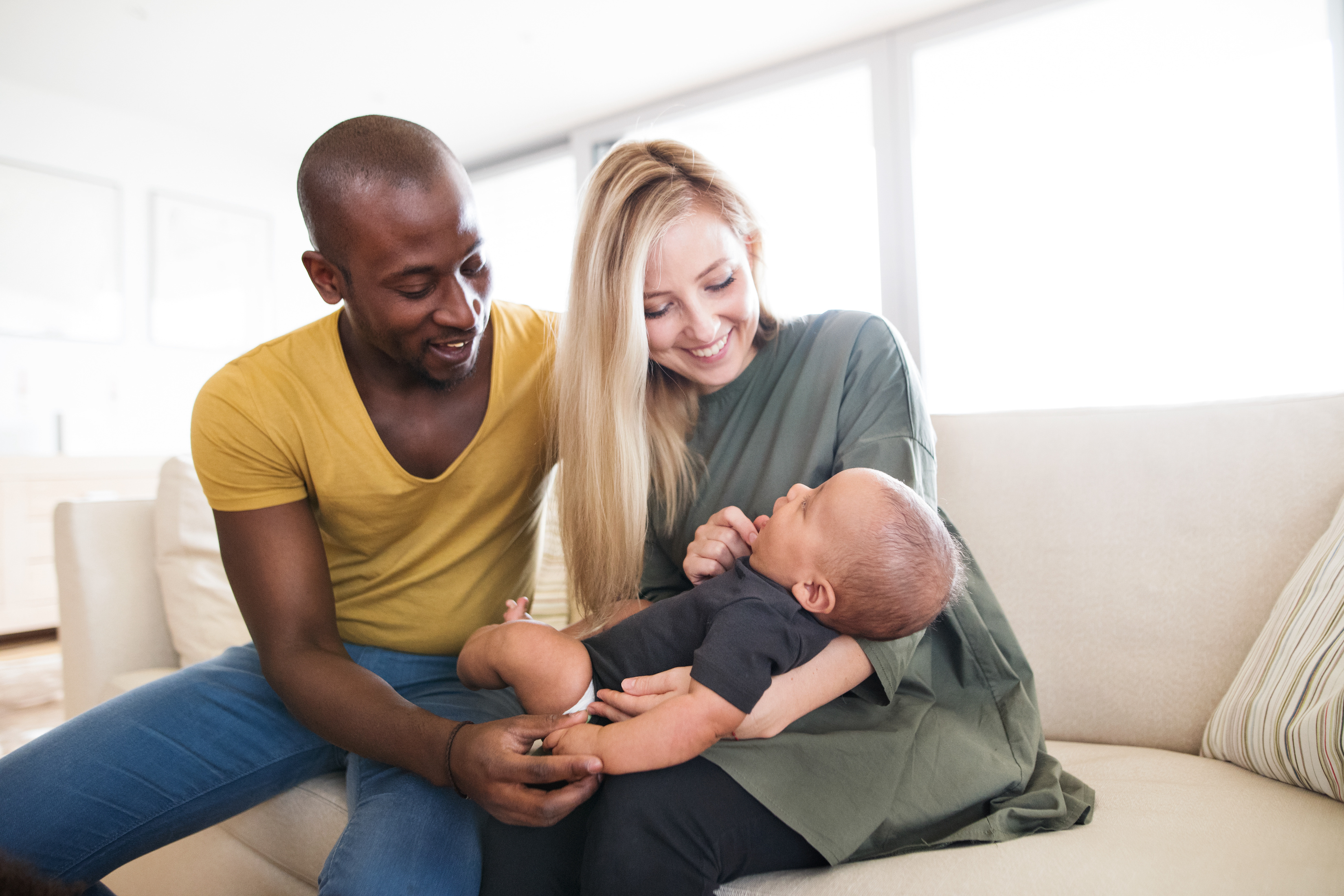A man plays with his baby's toes as his wife holds the child. Life changes, such as marriage and the birth of a child, often require updates to your existing will.