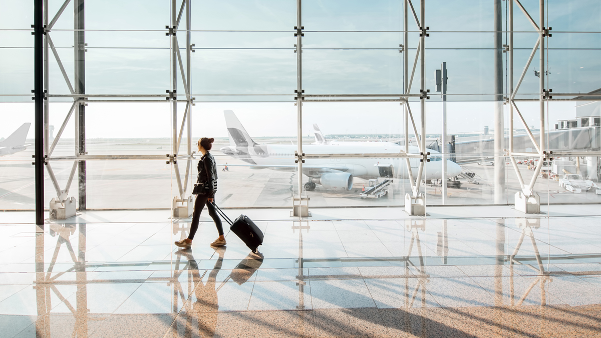 A woman walks through an airport. Tracking, documenting, and reimbursing employees for their business travel expenses can be a pain. Simplify with a per diem deduction.
