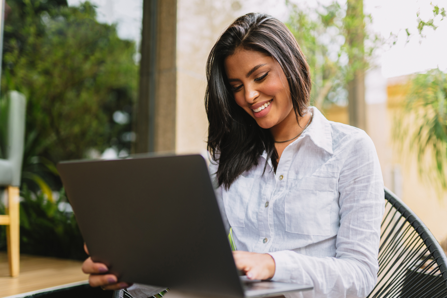 A woman seated outside at a cafe looks at her open laptop while reading about Texas LLCs. Documents must be filed with the Texas Secretary of State, and you should research whether your Texas LLC name is available.