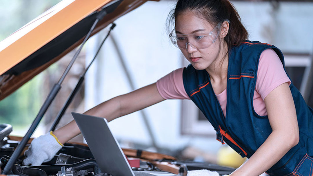 A mechanic checks the oil on a car in her car repair shop. She might consider a “doing business as” (dba) name to establish her company’s unique brand identity. 