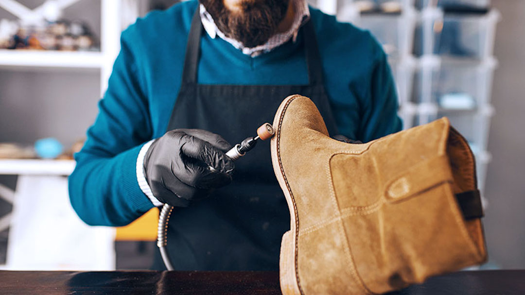 A shoe cobbler cleans a work boot at his shop, which he registered as a New York dba.