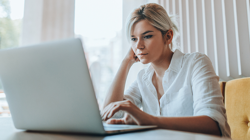 woman leaning on her arm looking at her laptop