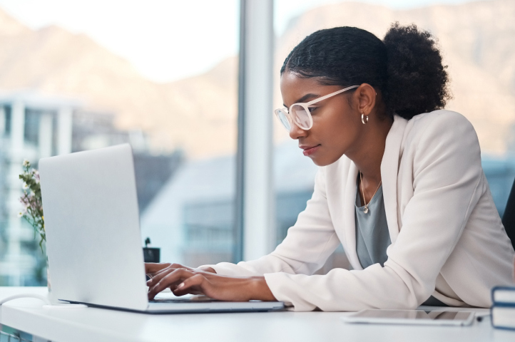 A woman sits at a desk while typing up an LLC operating agreement for her business.