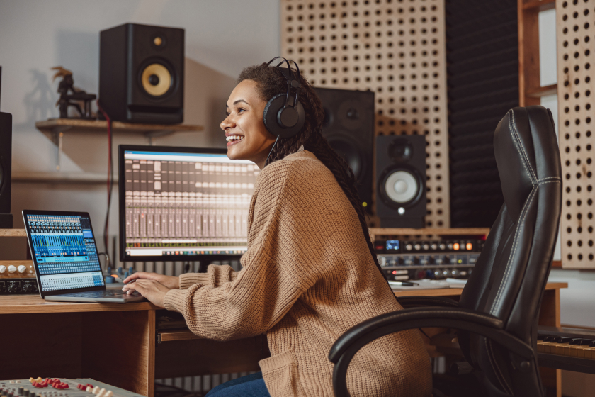 A woman seated in a chair wears headphones as she listens to and edits music. Learn how to pay yourself in an LLC if you have an LLC.