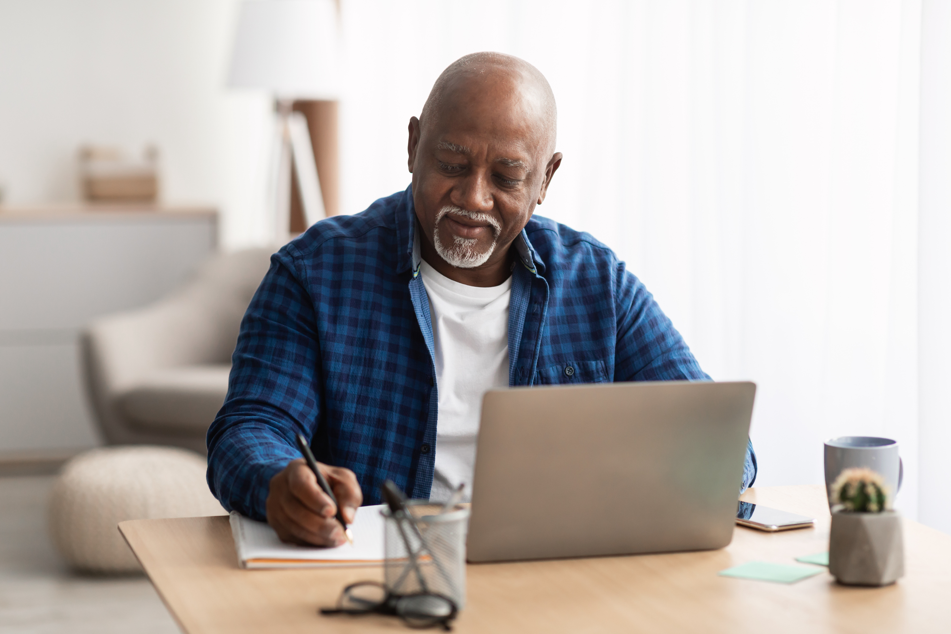 A man jots down a note while reading online about wills. Creating a will is a crucial step in estate planning.