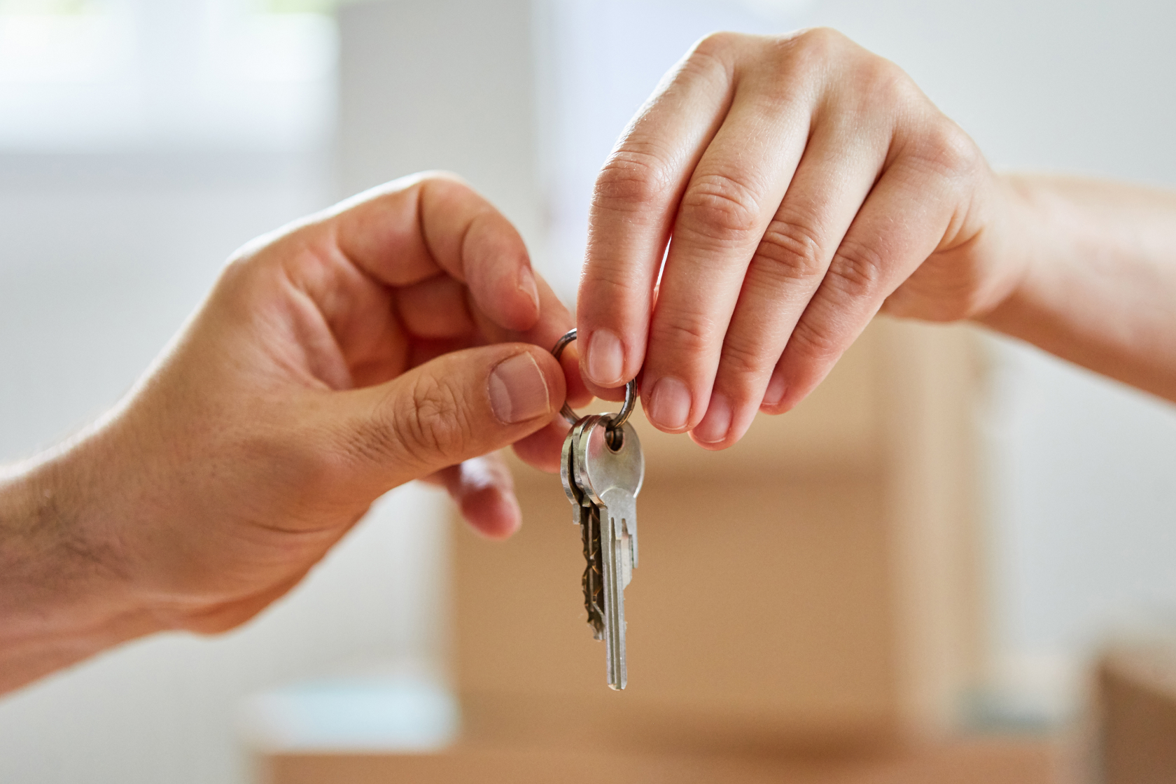Two hands hold the same pair of keys as they take ownership of common property. Learn the basics of joint tenancy vs. tenants in common.
