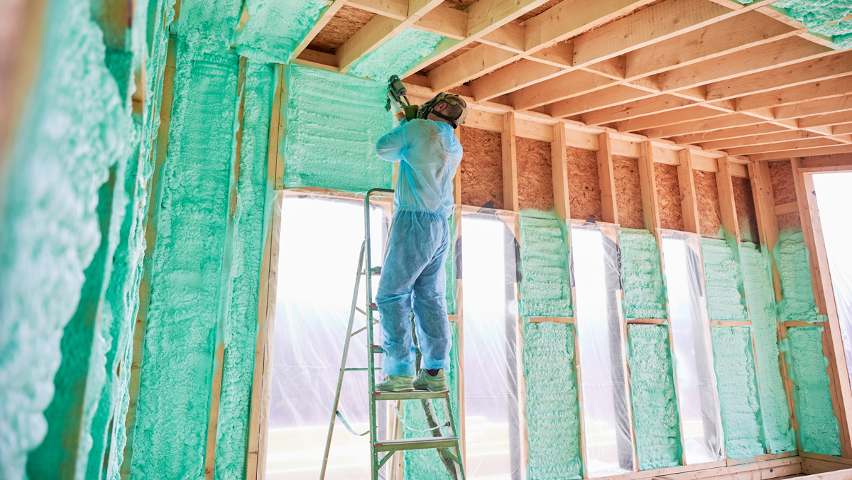 A man installs insulation in a new building.