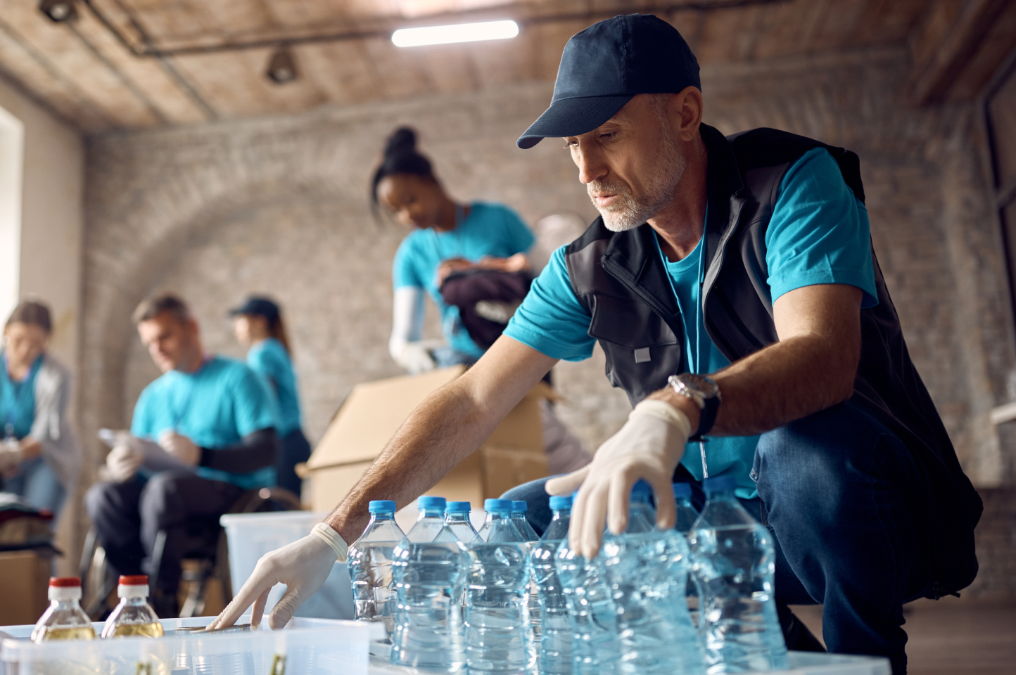 A man in a vest with a logo arranges water bottles for his nonprofit. If you're  Thinking of pursuing tax-exempt, nonprofit status, be certain you understand what it means first.