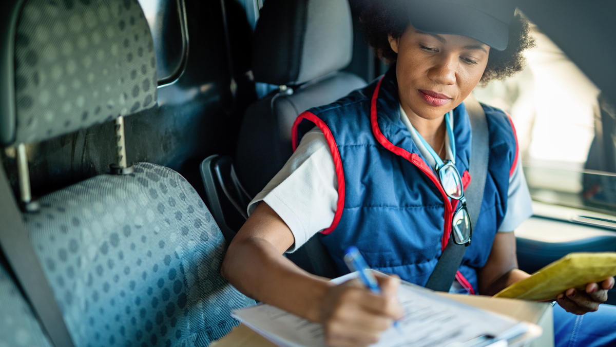 A woman makes notes before making a delivery. She may be eligible for a tax break for buying a vehicle.