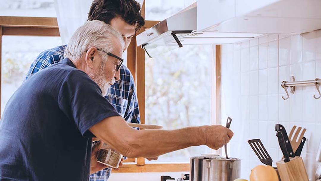 An elderly man is helped in the kitchen by his son. When creating a will in Texas, selecting a reliable and responsible executor is critical. 