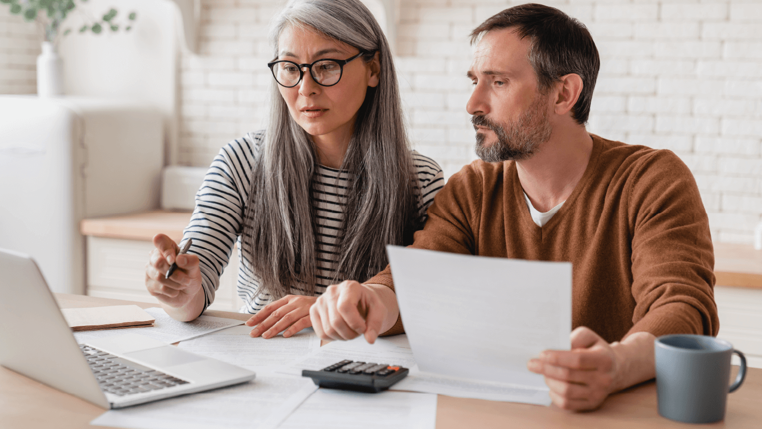 A man and woman examine documents in front of an open laptop while considering bankruptcy options.