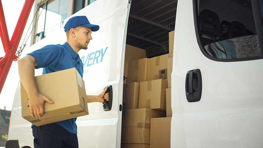 delivery driver in a blue shirt carrying  a box 