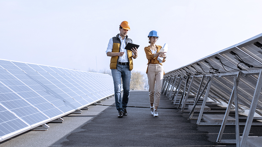 man and woman wearing hard hats and inspecting solar panels 