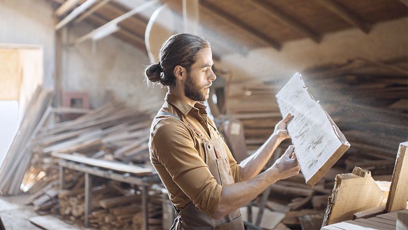 man working in woodshed cutting wood 