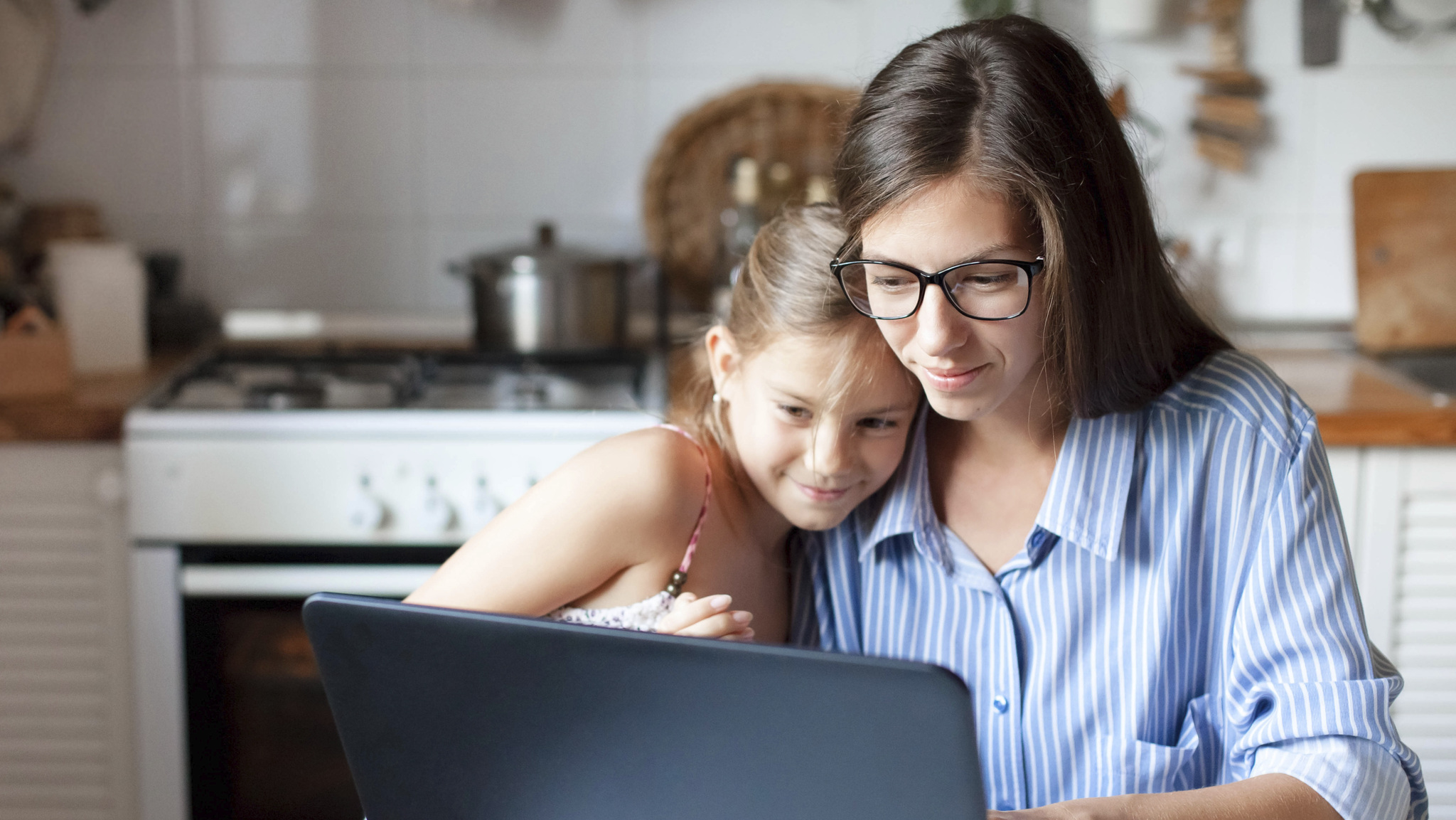 mother and daughter looking at laptop in the kitchen 