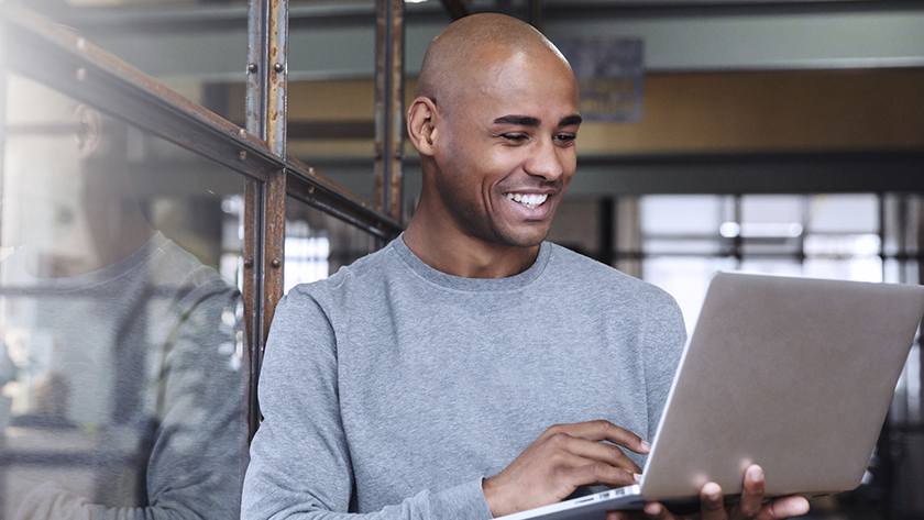 smiling man standing in a door way with his laptop