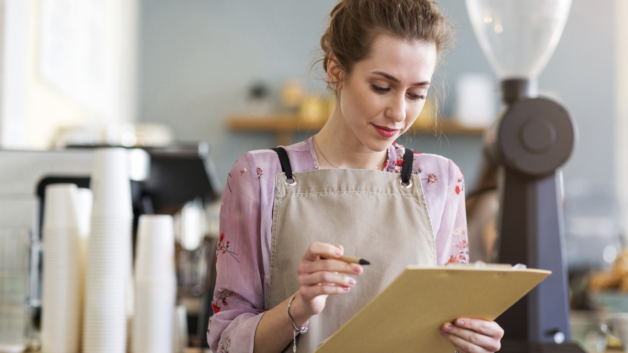 woman in apron looking at clipboard