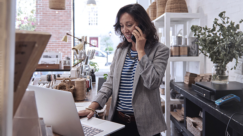 woman in grey jacket and striped shirt working in her office 