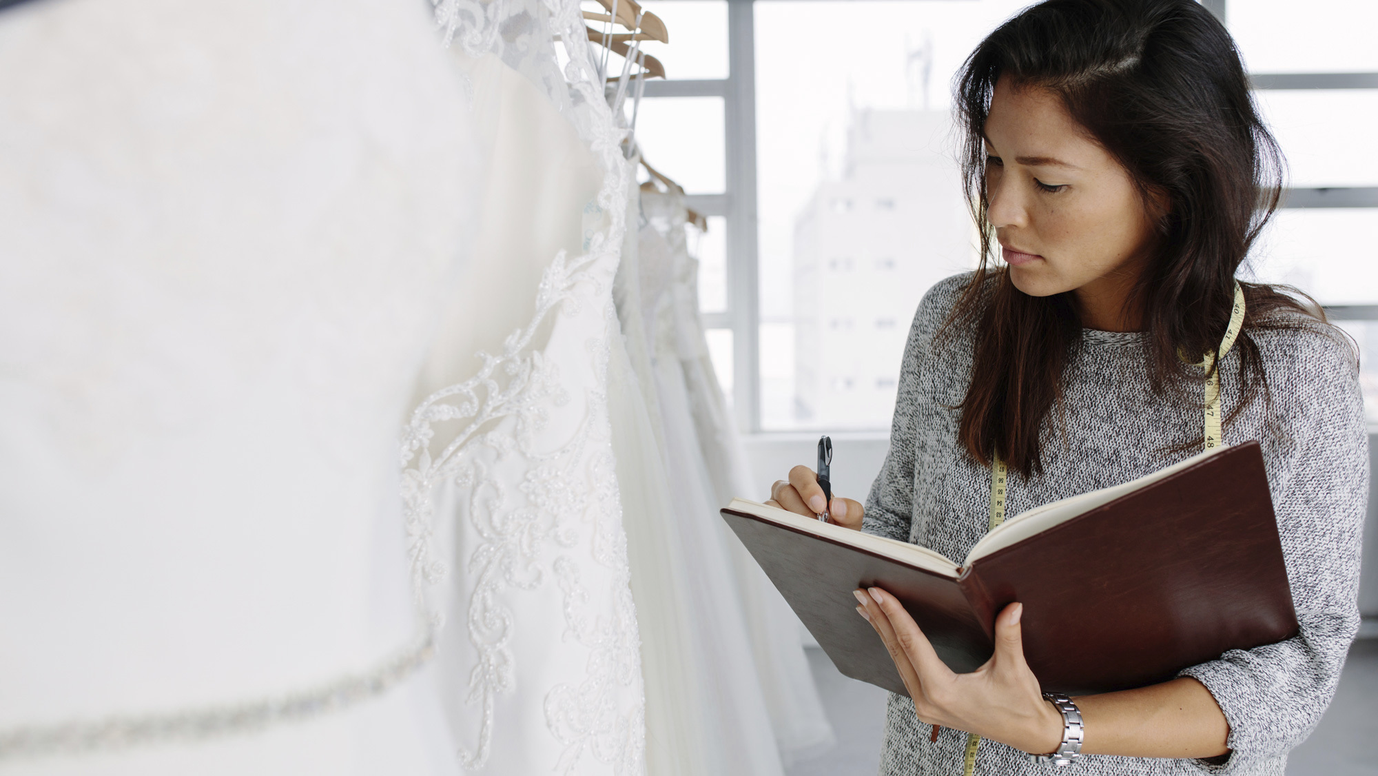 woman looking at notebook in wedding dress shop
