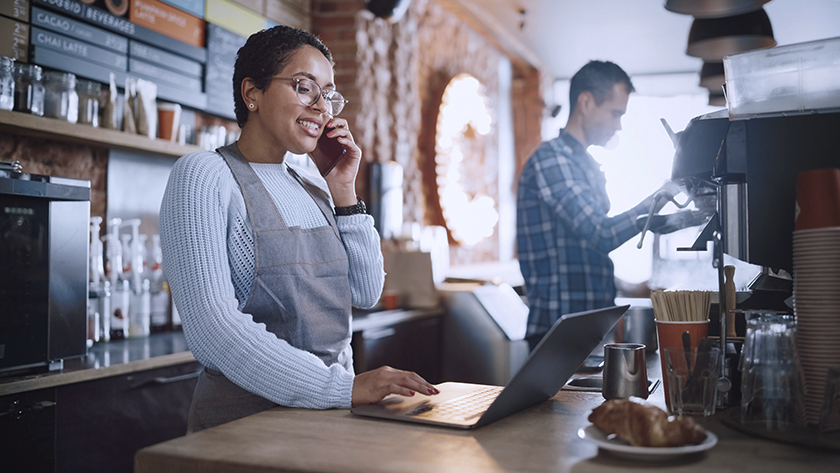 woman taking order on laptop in a cafe