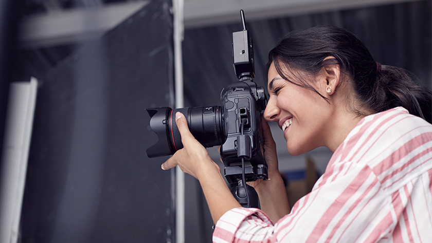 woman taking pictures with DSLR camera wearing pink striped shirt 