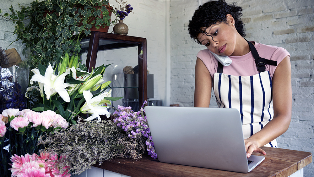 woman wearing an apron taking orders at a flower shop