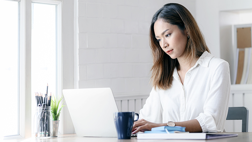 woman wearing white shirt working at laptop in home office
