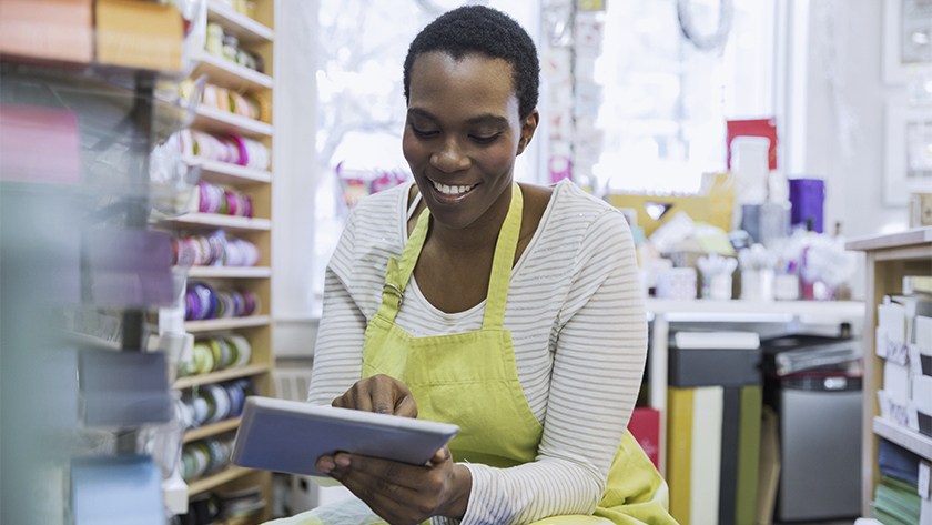 woman wearing yellow apron looking at tablet in a store 