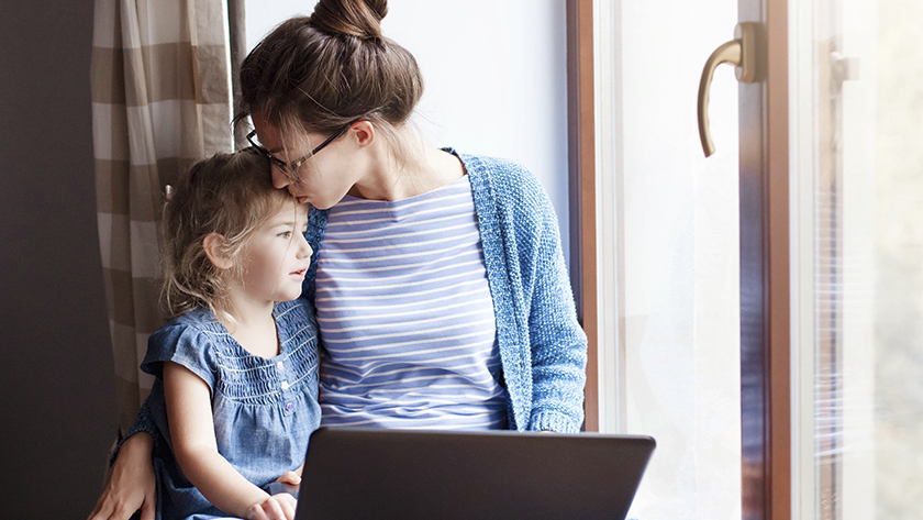 woman with child on her lap looking at laptop 