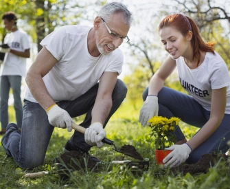 Older man with gray hair working as a volunteer planting trees with a woman with red hair wearing a volunteer shirt working for a nonprofit organization that was formed with LegalZoom.