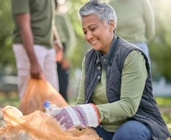 Latina woman with short salt and pepper hair wearing a black puffer vest and green shirt volunteering at a recycling nonprofit that was started with LegalZoom.