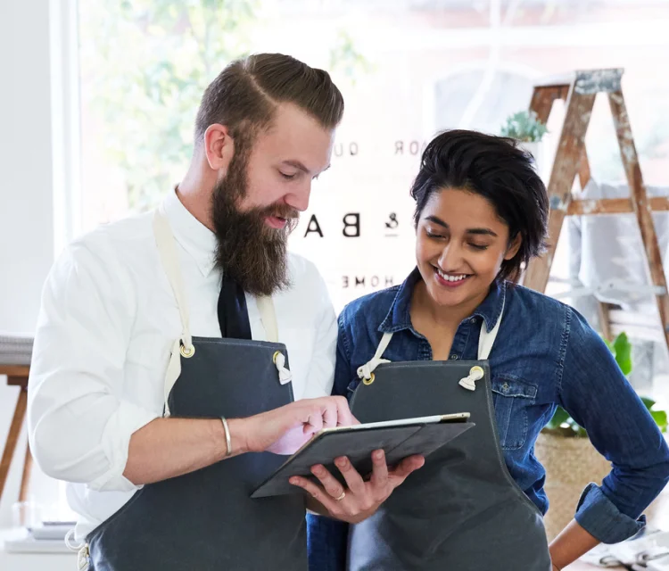 A business owner signs electronic documents using LZ's electronic signature solution and explains the benefits of electronic signatures over wet signatures to an employee.